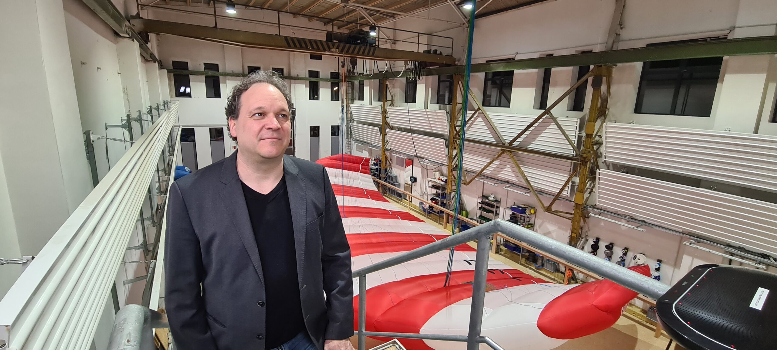 Stephan Wrage, CEO of Skysails, in a hall with a kite laid out on the floor.