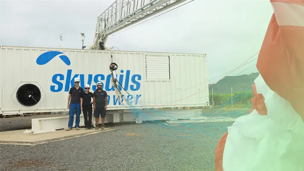 About Us – Skysails employees in front of a kite ground station with the crane folded down and the kite stowed.