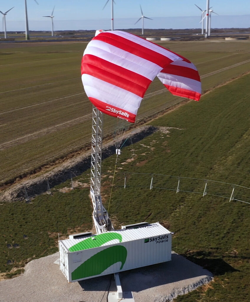 News Blog – a Skysails kite at the ground station in front of a wind farm.